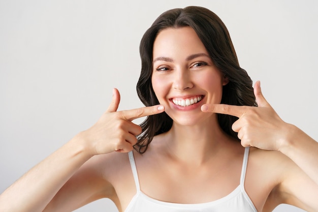 Bella giovane donna con un sorriso perfetto. Isolato su bianco. Donna dopo la procedura di sbiancamento dei denti