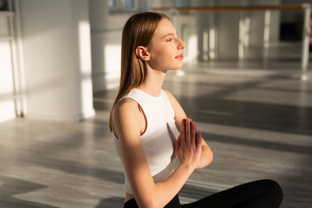 bella giovane donna con una figura snella è impegnata nello yoga nella hall