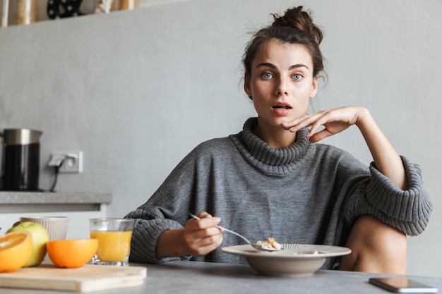 Bella giovane donna con una sana colazione seduti su una cucina