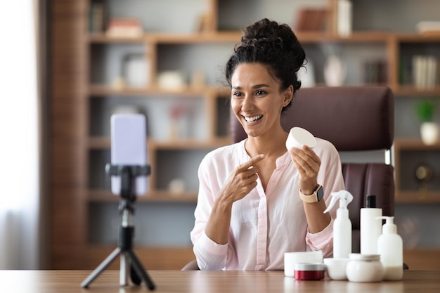 Bella giovane donna consulente di bellezza in streaming da casa che mostra i cosmetici