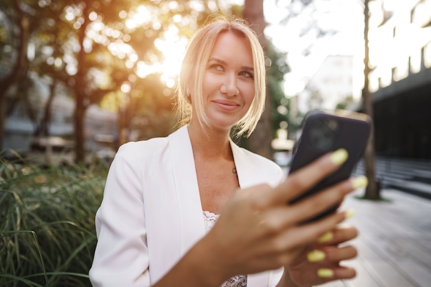 Bella giovane donna d'affari bionda che utilizza smartphone in città