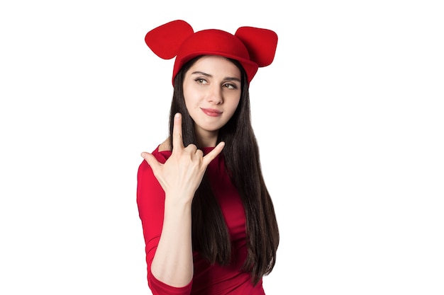 Bella giovane donna dai capelli neri bianca con il cappello delle orecchie del mouse e gesto della mano di musica rock.