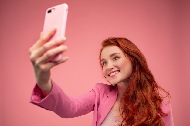 Bella giovane donna della testarossa che fa selfie