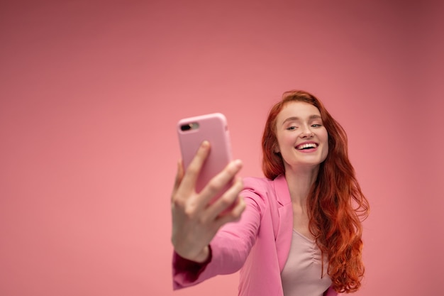 Bella giovane donna della testarossa che fa selfie