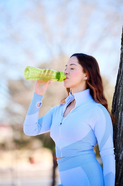 bella giovane donna europea in abbigliamento sportivo acqua potabile dopo l'allenamento