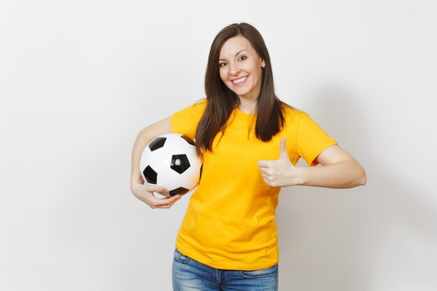 Bella giovane donna europea, tifoso o giocatore in uniforme gialla che tiene il pallone da calcio che mostra pollice in su isolato su sfondo bianco. Sport, giocare a calcio, salute, concetto di stile di vita sano.