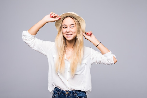 Bella giovane donna felice in cappello di paglia sopra il muro grigio