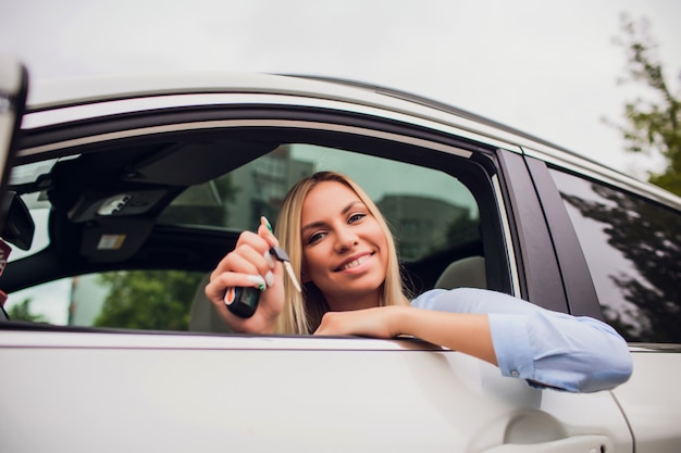 Bella giovane donna felice in nuova automobile con le chiavi - all'aperto