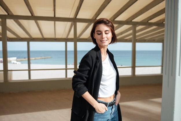 Bella giovane donna felice in piedi e sorridente nel gazebo sulla spiaggia