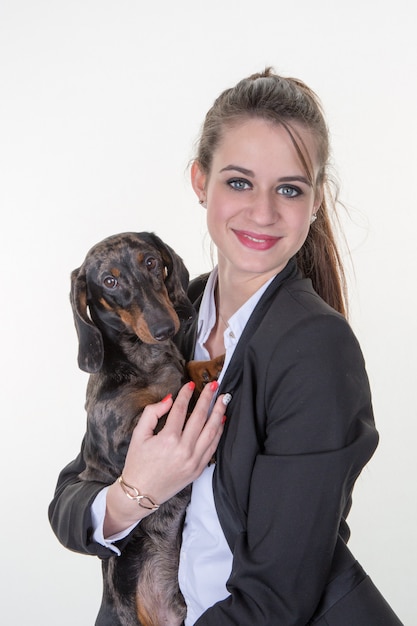 Bella giovane donna graziosa con un cane in braccio