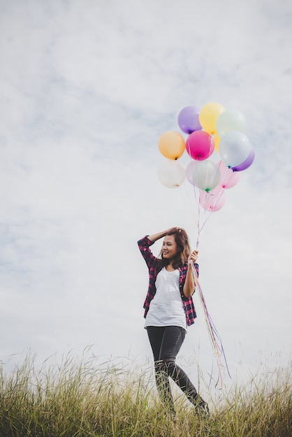 Bella giovane donna hipster tenendo con colorato palloncini all&#39;aperto, Libertà godere con la natura. Concetto di stile di vita delle donne.