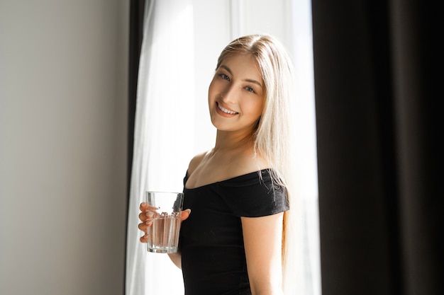 bella giovane donna in abiti sportivi con un bicchiere d'acqua