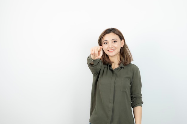 Bella giovane donna in abito casual in piedi sopra il muro bianco. Foto di alta qualità