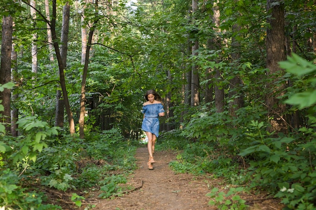 Bella giovane donna in abito che corre nella foresta estiva