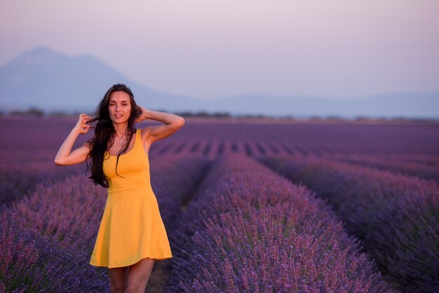 bella giovane donna in abito giallo rilassarsi e divertirsi sul campo di lavanda fiore viola