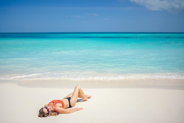 Bella giovane donna in bikini sexy che risiede sulla spiaggia del mare. Tempo libero tropicale della sabbia bianca di vista sul mare azzurro