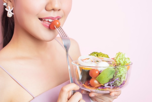 Bella giovane donna in buona salute che mangia insalata su priorità bassa dentellare