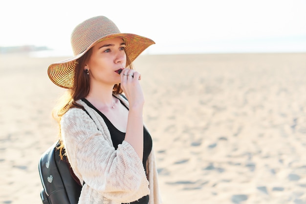 Bella giovane donna in cappello di paglia sulla spiaggia
