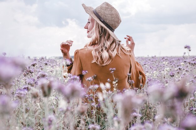 Bella giovane donna in cappello in campo di lavanda. fiori che sbocciano