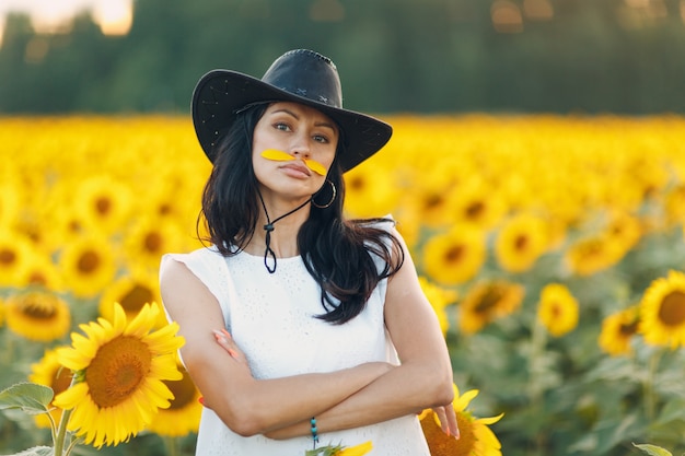 Bella giovane donna in cappello sul campo di girasoli.