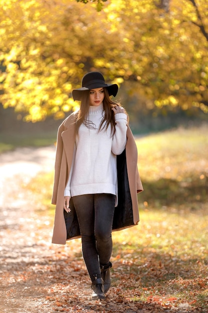 Bella giovane donna in cappotto e cappello nero