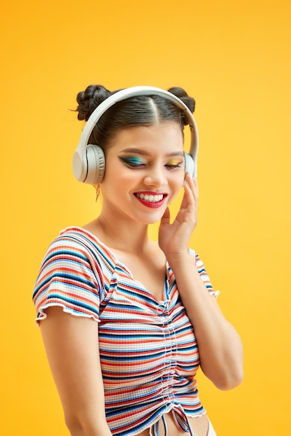 Bella giovane donna in cuffia che ascolta musica su sfondo colorato