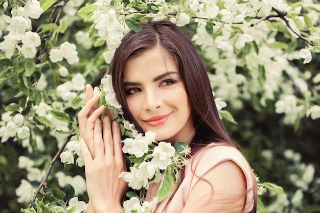 Bella giovane donna in fiore fiori di primavera sfondo Cute ragazza sorridente all'aperto