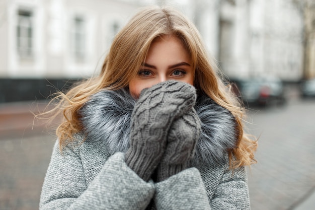 Bella giovane donna in guanti a maglia vintage nasconde il viso dal freddo