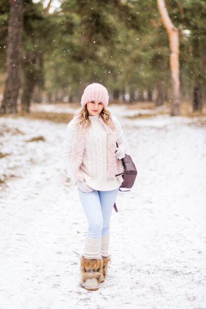 Bella giovane donna in jeans e giacca rosa nella foresta invernale