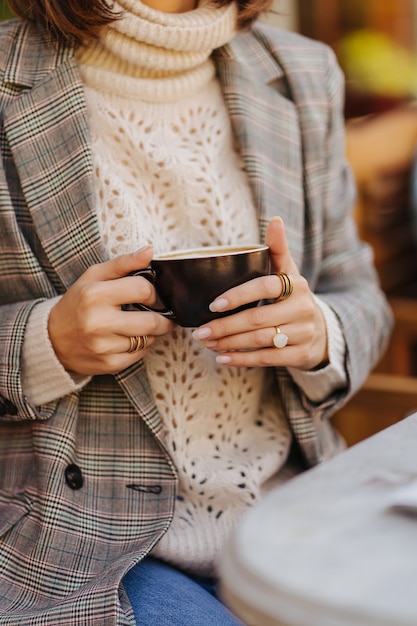 Bella giovane donna in maglione caldo che beve caffè. Mattina d'autunno.