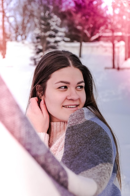 Bella giovane donna in maglione lavorato a maglia nel parco invernale. Freddo all'aperto. Neve Ritratto sorridente felice della ragazza. Moda invernale