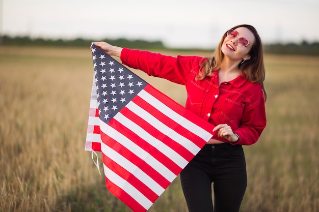 bella giovane donna in occhiali da sole rosa con bandiera americana