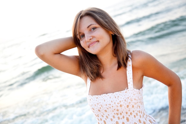 Bella giovane donna in piedi sulla spiaggia