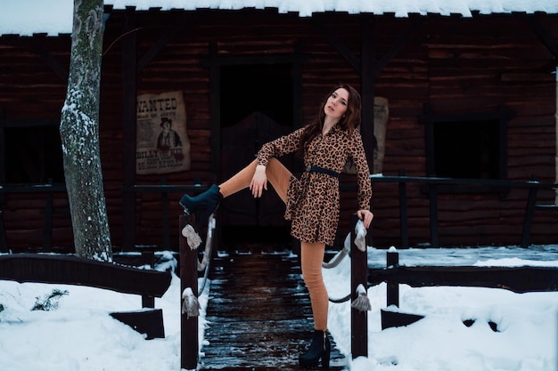 Bella giovane donna in posa in un abito leopardato in una sera d'inverno in un parco cittadino