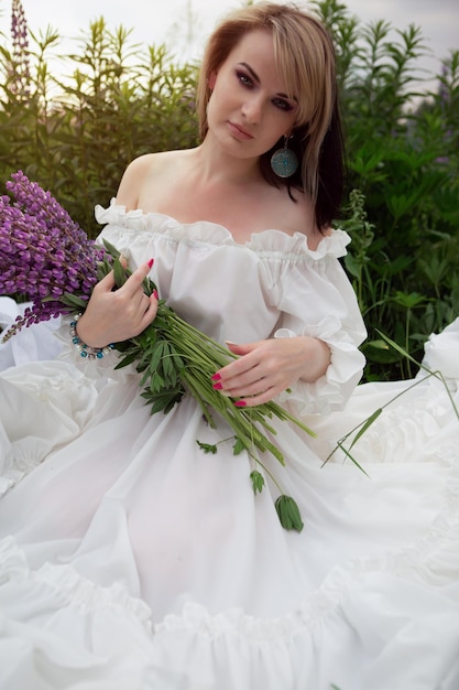 Bella giovane donna in un campo di lupini in fiore