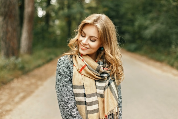 Bella giovane donna in un'elegante sciarpa vintage passeggiate nel parco in una giornata autunnale.