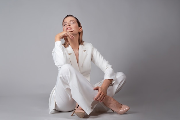 Bella giovane donna in un vestito bianco alla moda e scarpe a tacco alto beige,