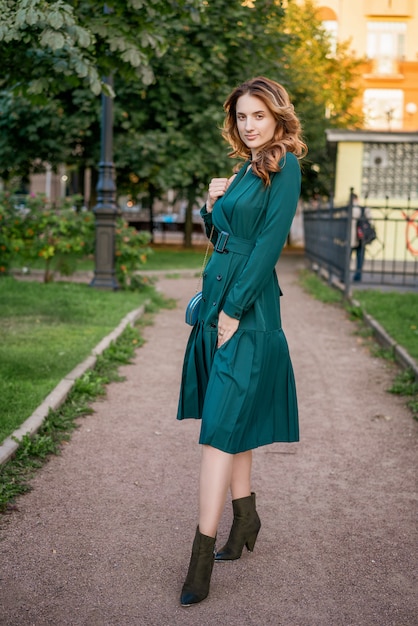 Bella giovane donna in una passeggiata in un abito verde.