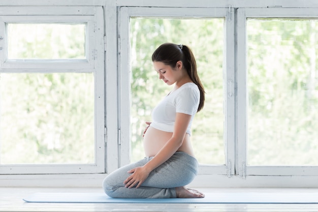 Bella giovane donna incinta che fa yoga