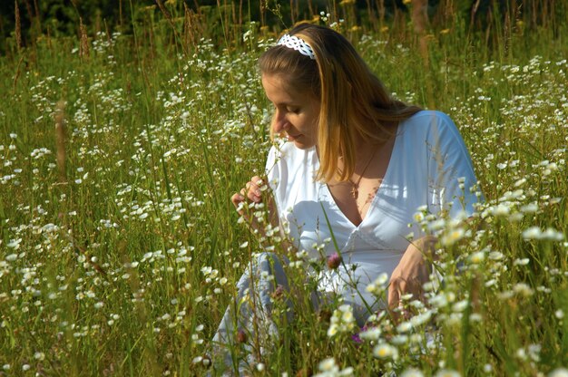 Bella giovane donna incinta con una pancia nuda seduta in un fiori al prato.