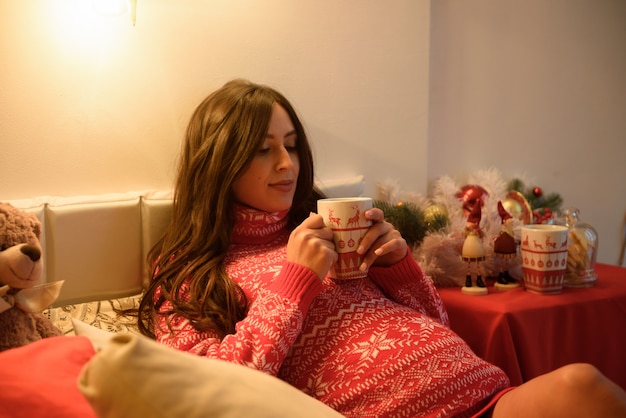 Bella giovane donna incinta su un Natale, riposando durante le vacanze di Natale. Grande pancia incinta