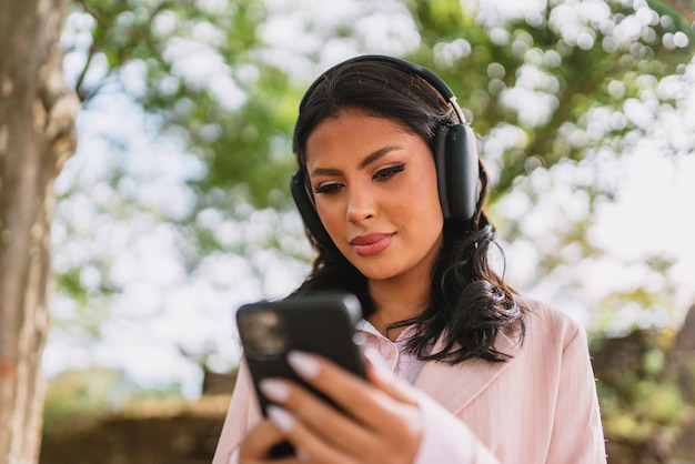 Bella giovane donna latina che utilizza smartphone in piedi sulla strada della città