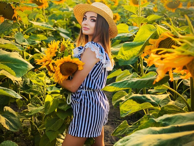 Bella giovane donna nel campo di girasoli il giorno d'estate