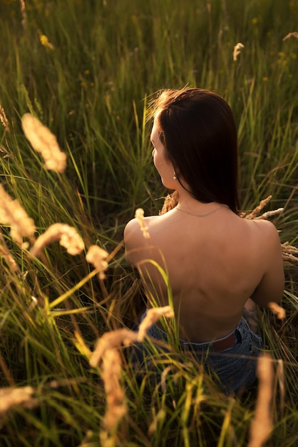 Bella giovane donna nel campo di grano al tramonto Vista posteriore
