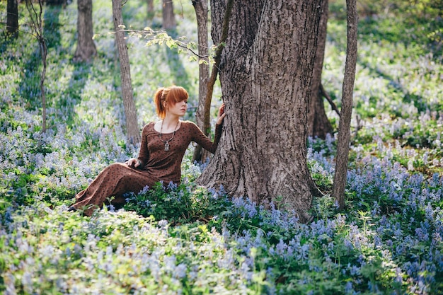 Bella giovane donna nella foresta con fiori di primavera