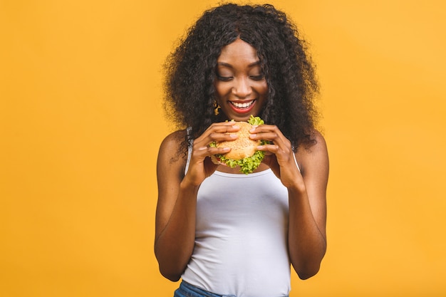 Bella giovane donna nera afroamericana che mangia hamburger