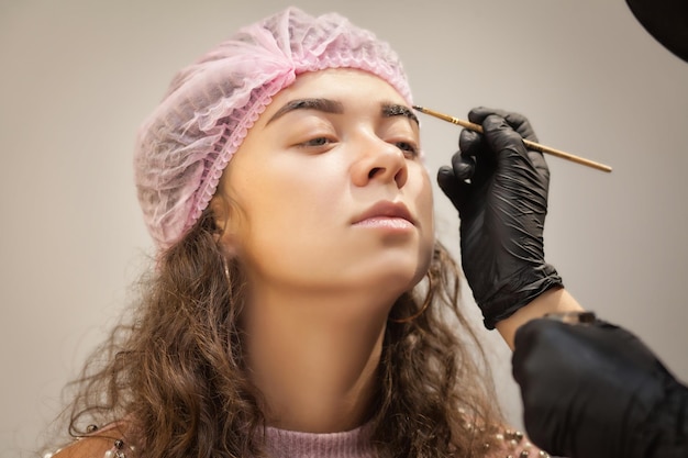 Bella giovane donna ottiene la procedura di correzione delle sopracciglia Giovane donna che dipinge le sopracciglia nel salone di bellezza