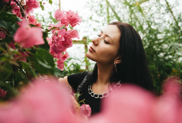 Bella giovane donna profumati fiori di primavera Bellissimi fiori di bouganville nella mano di una ragazza con capelli scuri fluenti