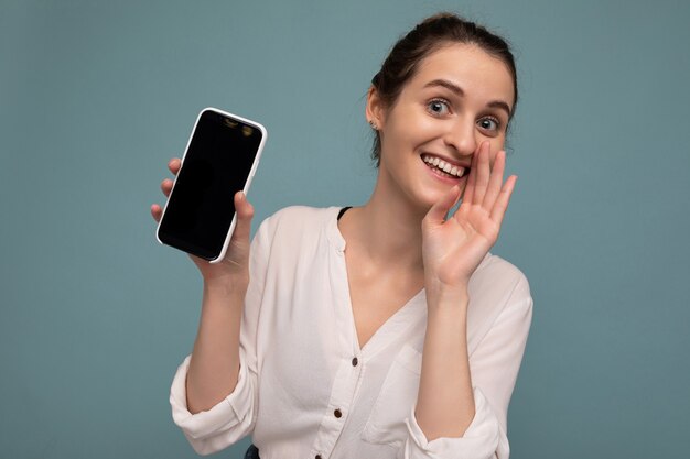 Bella giovane donna riccia bionda positiva che indossa una camicia bianca casual e isolata sopra l'azzurro