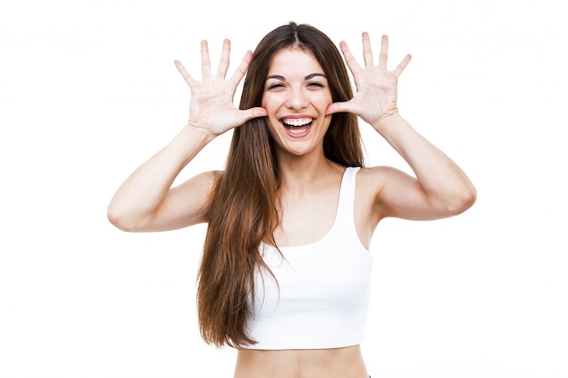 Bella giovane donna scherzando e facendo divertente viso su sfondo bianco.